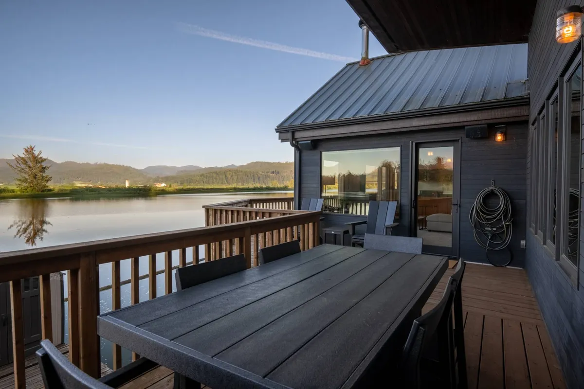 An outdoor dining table perched beside the river, with a scenic mountain background. The tranquil setting invites guests to relax, dine, or sip coffee while enjoying the riverside views and abundant nature.
