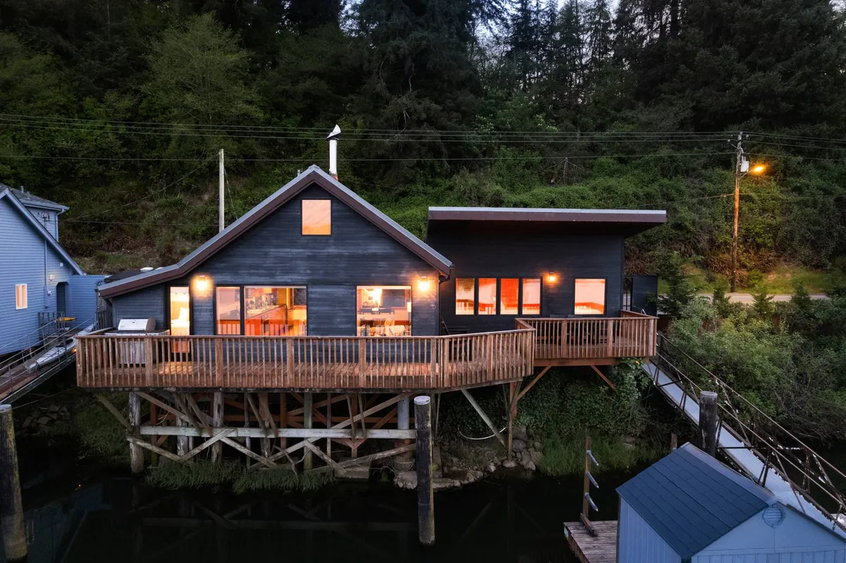 The image showcases an exterior view of a wooden deck surrounded by lush greenery and large windows, highlighting the seamless indoor-outdoor flow. The deck offers a safe, contained space to enjoy sunsets, while the surrounding nature invites scenic walks for leashed pets.